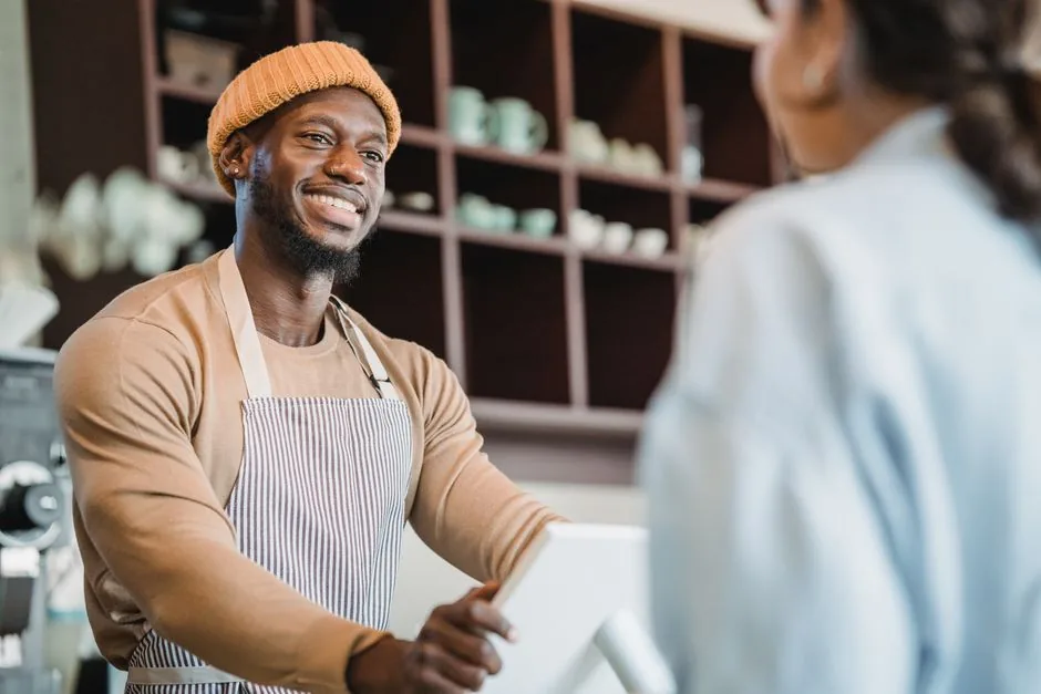 Atendente sorrindo ao atender cliente no balcão