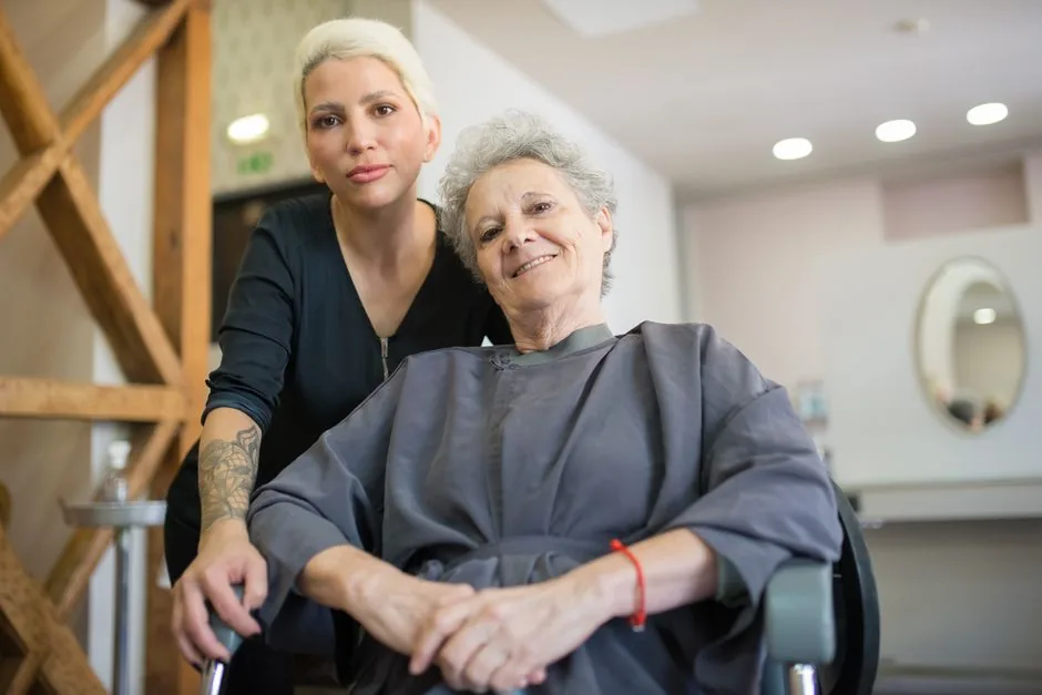 Cabeleireira sorrindo ao lado de uma cliente no salão